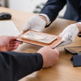 白手袋を着用した査定士が、買取金を顧客に手渡している様子